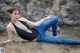 A woman in a black top and blue jeans laying in the water.