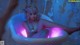 A woman sitting in a bathtub with a pink light.