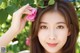 a woman holding a pink flower in front of her face