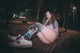 A woman sitting on a bench in a park at night.