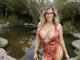 A woman in a red dress and glasses posing by a pond.