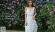 a woman in a white dress standing in front of pink flowers