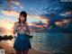 A woman in a blue dress standing on a beach.